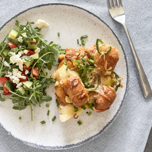 Spicy croissant casserole served on a plate with a side salad