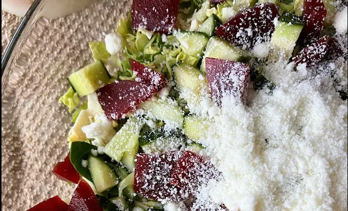 Close-up of arugula salad with pickled beets, cucumber and grated cheese