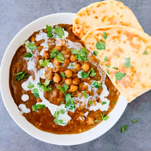 Easy chickpea curry (chole) in a white bowl with naan on the side