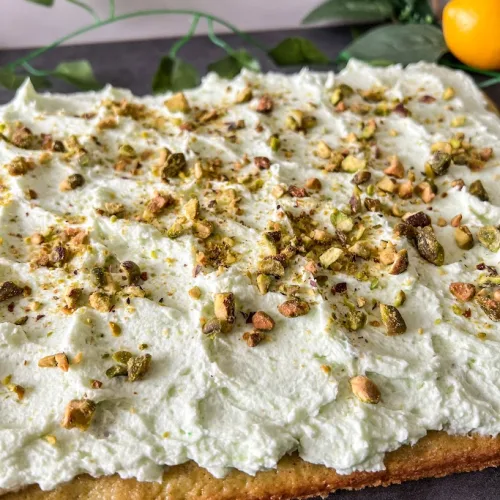 Pistachio cloud cake topped with whipped cream and chopped pistachios