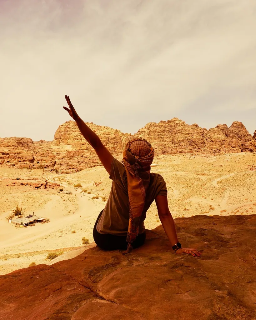 Shikha waving from a clifftop in Petra, Jordan