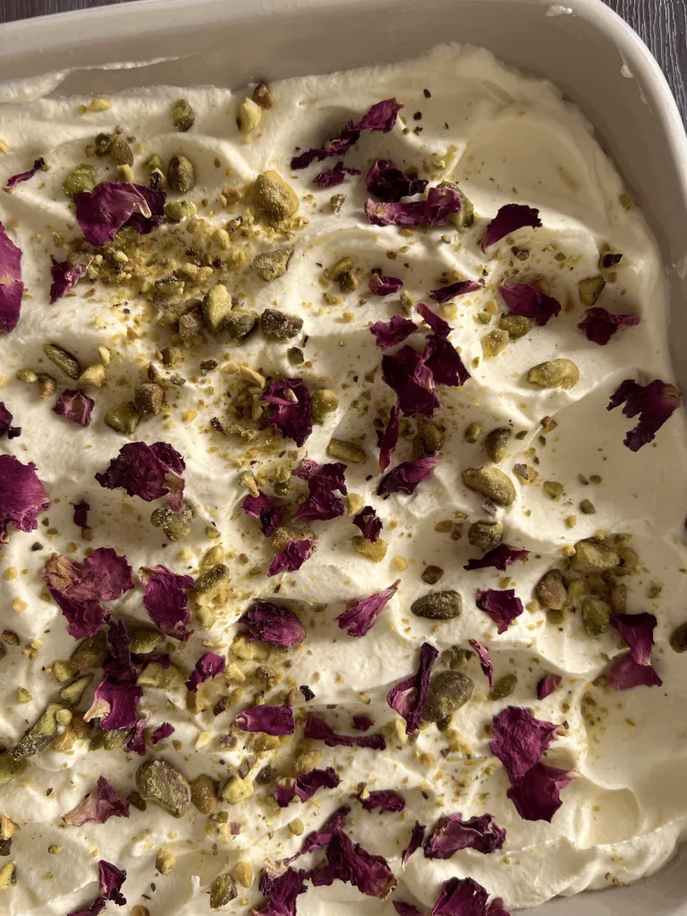 Whole rasmalai tres leches cake topped with dried rose petals and pistachios